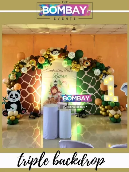 This triple backdrop design adds so much depth to a jungle theme party. The two giraffe-print panels flank a central personalized banner, all framed by a beautiful organic balloon garland.