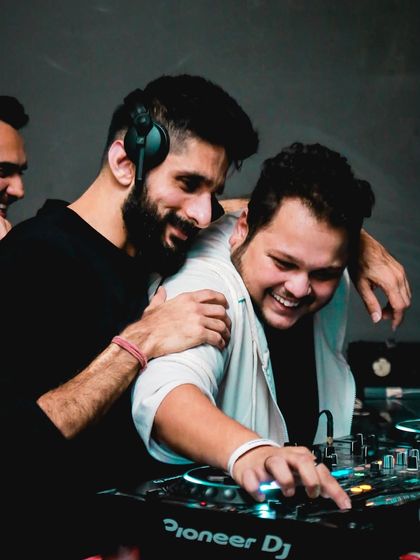 A fun, candid moment sharing a laugh with another DJ behind the decks. It's all about good vibes.