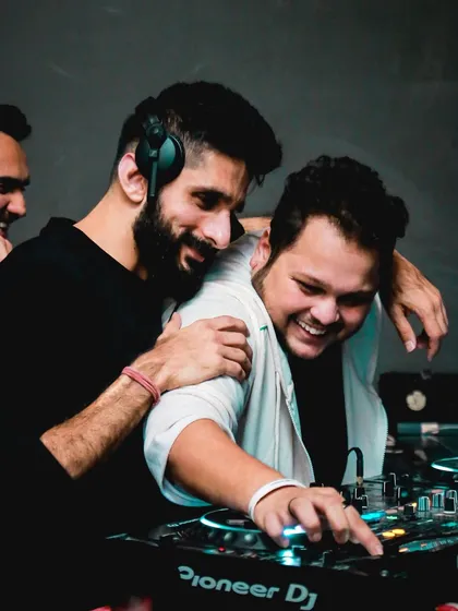 A fun, candid moment sharing a laugh with another DJ behind the decks. It's all about good vibes.