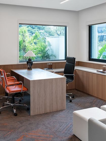 A private cabin in 'The High-Flying Office' with views of the lush exterior landscape. The room is furnished with a clean, modern desk and ergonomic chairs, creating a comfortable and productive environment for focused work.