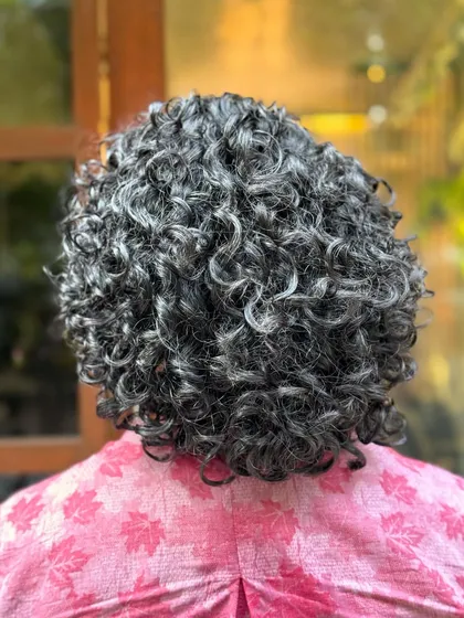 Showcasing the beauty of natural silver curls with a chic short haircut. This style is all about embracing texture and creating a sophisticated shape.