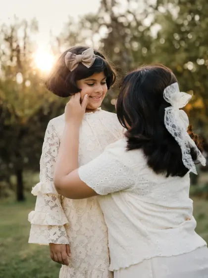 A mother adjusts her daughter's hair during a golden hour photoshoot. This sweet, candid interaction is what makes these sessions so special.