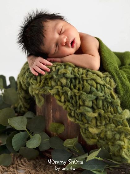 An earthy, nature-inspired setup using a wooden bucket, a chunky green knit, and eucalyptus leaves for a rustic and organic feel.