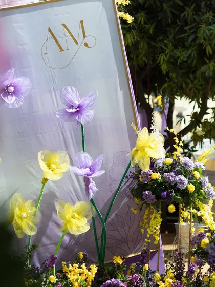 A close-up of the custom-made oversized flowers and the couple's monogram, key elements of the pastel Haldi decor.