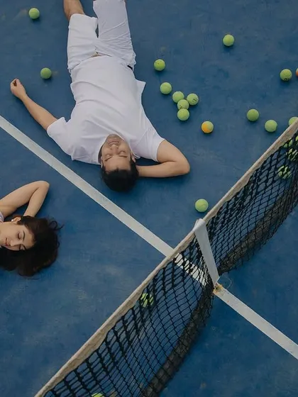 A unique perspective on a couple's shared passion. This overhead shot on a tennis court shows how we love to create playful and personal pre-wedding shoots that reflect who you are as a couple, turning a simple game into a beautiful memory.