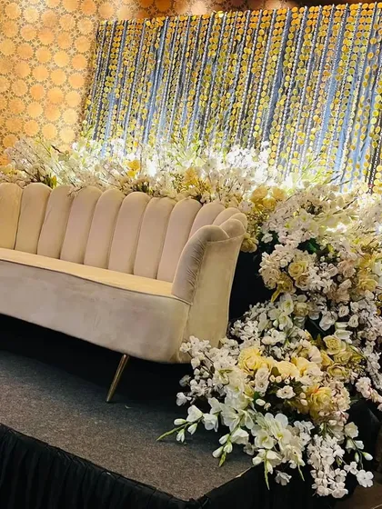 A close-up of a stage corner, showing the texture of the shimmering gold string backdrop against the lush white floral arrangements. The contrast creates a look of pure glamour.