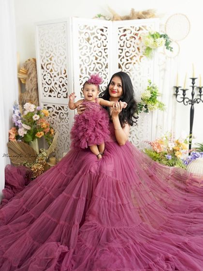 A joyful mother-daughter moment. The baby's happy expression while being held by her mom in a matching gown is absolutely priceless.