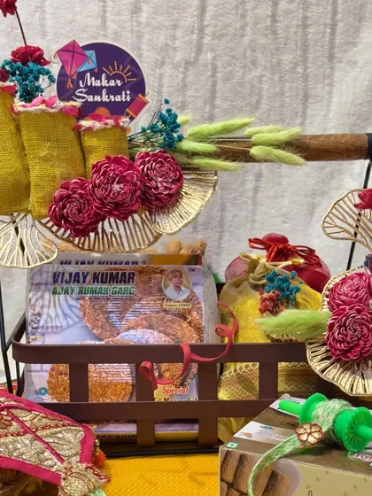 A beautiful Lohri hamper featuring a decorative stand and an assortment of traditional sweets. The floral and kite-themed decorations add to the festive charm.