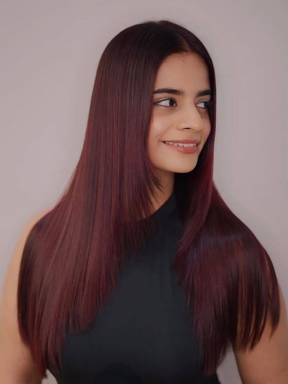 Our client looking radiant in her new raspberry red hair, a bold color choice that exudes confidence.
