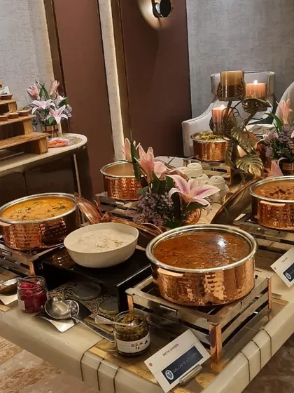 A closer look at the main course section of an intimate party, with rich curries served in gleaming copper pots.