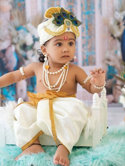 A curious little Krishna looking out from his seat. The vibrant colors and intricate details of this themed shoot make it truly special.