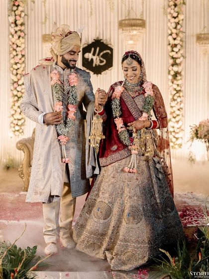 Shelly and Shivam walking hand-in-hand after their ceremony, surrounded by smoke for a magical effect.