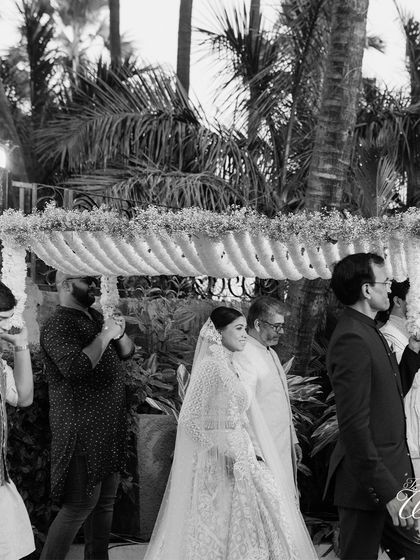 A timeless black and white shot of the bridal procession. This captures the solemnity and emotion of the moment as the bride makes her way to the mandap.