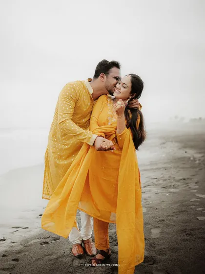 A sweet kiss on the cheek as they walk along the beach. This candid moment is full of warmth and affection from their pre-wedding shoot.