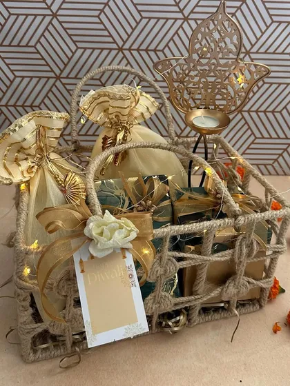 A rustic jute basket holding agate-print boxes and a leaf-design T-light holder. This hamper combines natural textures with a touch of festive gold, perfect for a warm and heartfelt Diwali wish.
