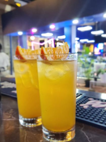 A pair of refreshing orange highball cocktails, garnished with orange slices and ready to be served. This classic mixed drink, composed of a spirit and a non-alcoholic mixer, is always a crowd-pleaser.