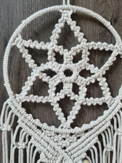 A close up of the star-shaped web at the heart of the dreamcatcher. This pattern is created using a series of carefully placed knots, forming a beautiful geometric design.