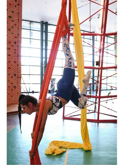 A student practices a challenging inverted hold, wrapping the silks around her body for support. Each class builds on the last to help you progress.