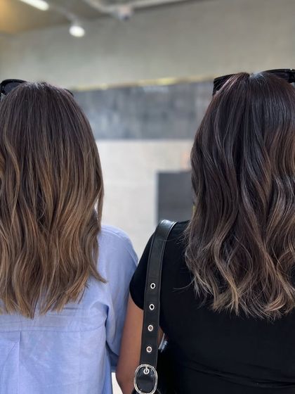 A shot of two friends, showcasing a light ash blonde and a smokey ash blonde balayage side-by-side. It shows the versatility of ash tones.