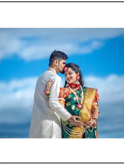 A loving forehead kiss, celebrating their journey in beautiful traditional clothing.