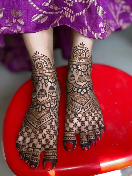 Your bridal mehandi is complete with beautiful feet designs. This intricate pattern features hanging jhumkas and detailed jaali work, ensuring you look stunning from head to toe.