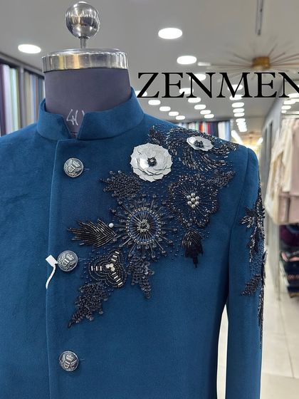 A close-up of the 3D floral handwork on the teal Jodhpuri. The mix of black beads and white fabric petals creates a beautiful contrast.