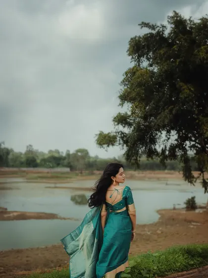 A wide shot of Mirnalini Ravi against a beautiful natural landscape. The simple styling allows her presence and the scenery to take center stage.