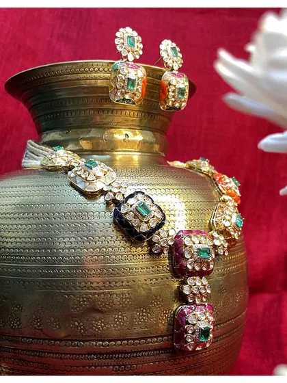 A vibrant polki set with multi-colored meenakari work. The combination of ruby, emerald, and navy blue enamel adds a touch of royalty to any festive occasion.