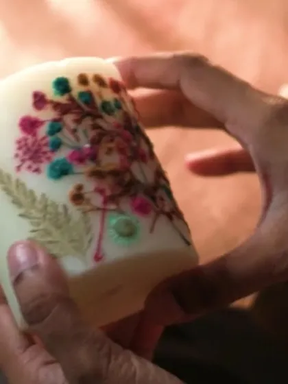 Holding our Floral Love Candle, you can see the intricate details of the real pressed flowers. Each one is a unique piece of art, handcrafted with love and positive energy.