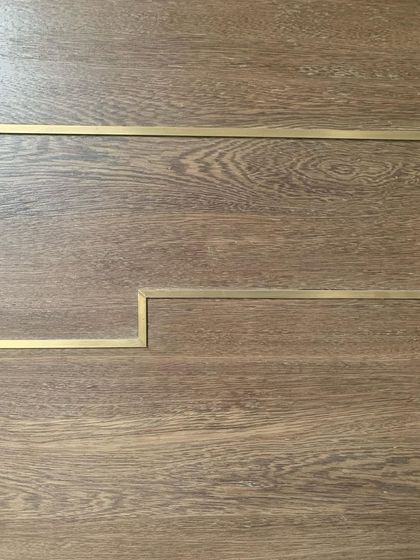 A close-up of oak flooring with a delicate brass inlay. This detail adds a touch of elegance and defines the transition between spaces with a subtle, handcrafted line.