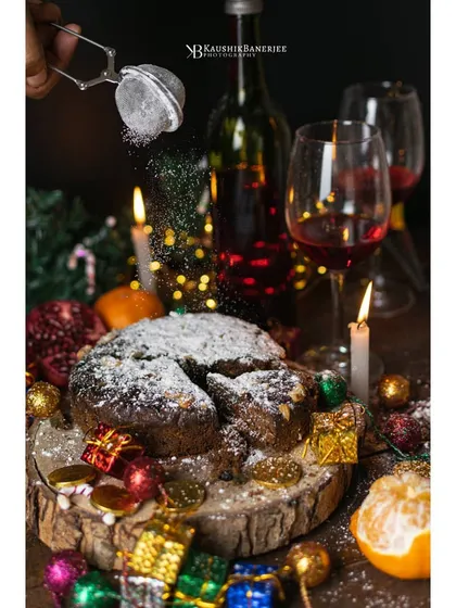 A festive Christmas cake scene, complete with the action of powdered sugar being dusted on top. This shot combines warm, celebratory lighting with a dynamic element to create a truly magical mood.