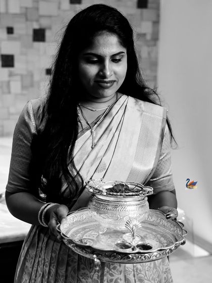 A black and white portrait of a woman holding a traditional silver vessel, creating a timeless and classic image.