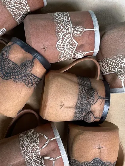 A pile of Déesse mugs, showcasing the black and white variations of the collection. These pieces are a labor of love, each one telling its own story.