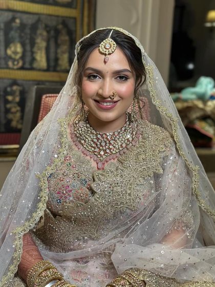 The smiling bride, showing how the soft updo and maang tikka frame her face beautifully.