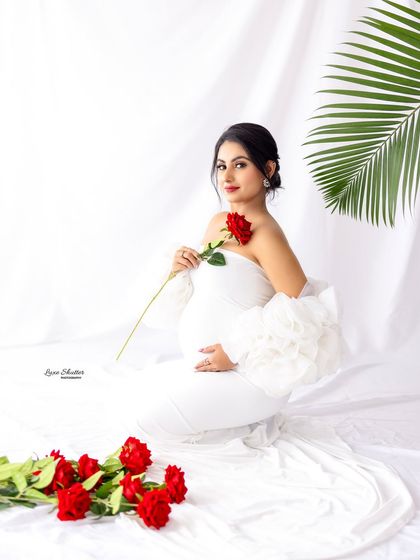 A beautiful seated portrait in a white gown, holding a single red rose. The simplicity of the setup makes the moment feel intimate.