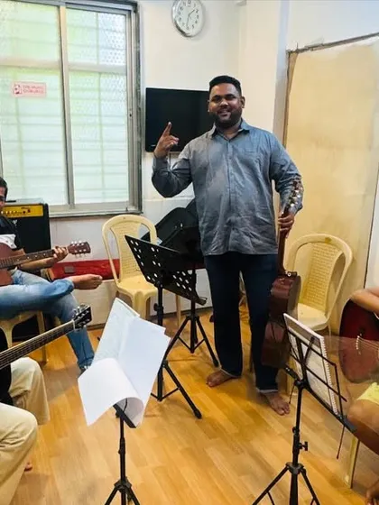 A proud moment in our guitar class. Our coach stands with his students, who are learning various techniques on both acoustic and electric guitars, fostering a fun and encouraging atmosphere.