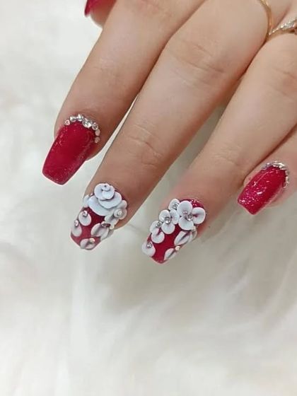 Perfect for a celebration, these square-tipped red nails are adorned with 3D white flowers and rhinestone borders at the cuticle.