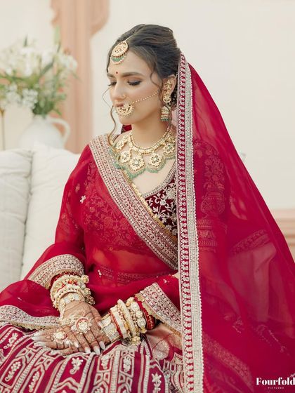 A serene portrait of Janvi. Her soft makeup, with a focus on a flawless base and defined eyes, perfectly complemented her traditional red bridal lehenga.