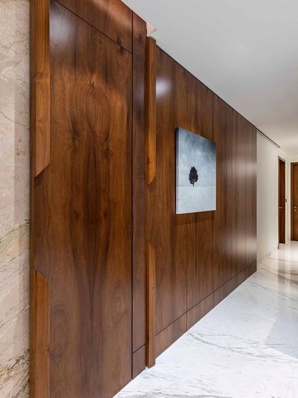 Luxury and style define this grand passage in a 4-bedroom Mumbai house. The centerpiece is a stunning 10-foot-wide sliding door, draped in rich veneer that exudes mid-century modern charm with a contemporary twist.