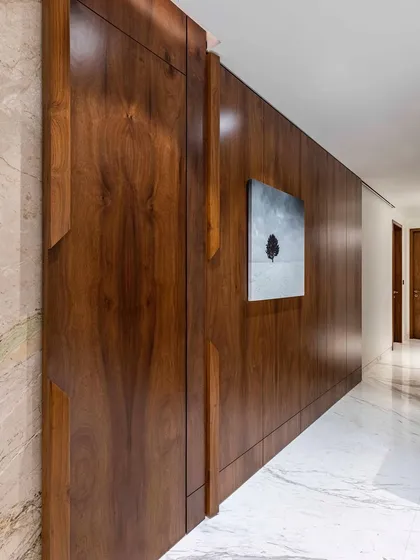 Luxury and style define this grand passage in a 4-bedroom Mumbai house. The centerpiece is a stunning 10-foot-wide sliding door, draped in rich veneer that exudes mid-century modern charm with a contemporary twist.