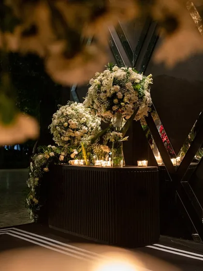 A detail shot of the cocktail night entrance, with large spherical arrangements of white flowers and the warm light of candles reflecting in the mirrored wall panels.