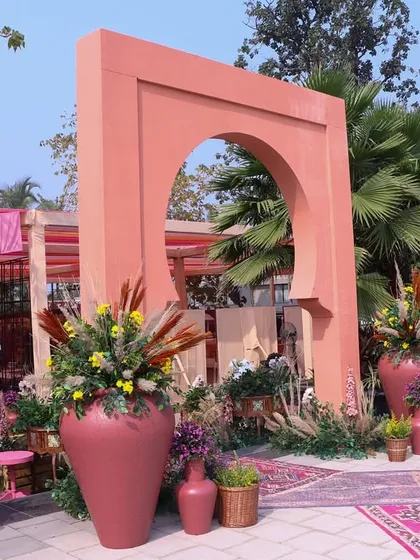 A wider perspective of the entrance arch, flanked by large terracotta urns filled with flowers, welcoming guests to the celebration.