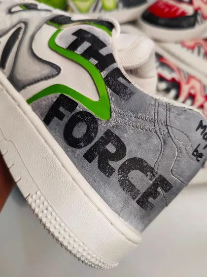 A detail shot of the Yoda shoe, with "May the Force be with you" painted on the heel. The textured grey background gives it a rugged, battle-worn look.