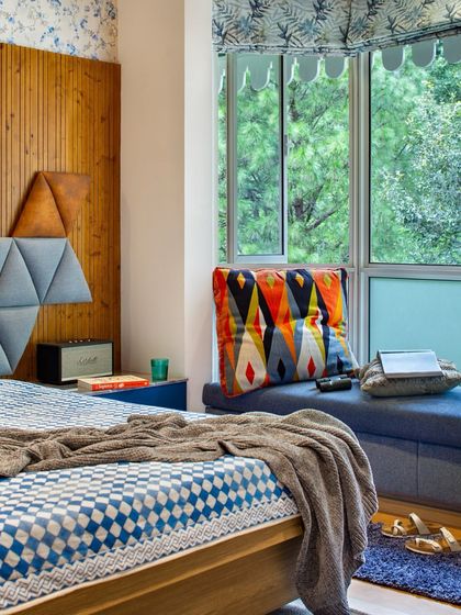 Another view of the kids' bedroom at Valley of Dreams, showing the cozy bay window seat with storage. The mix of a custom geometric headboard, warm wood, and colorful textiles creates a space that is both functional and full of youthful spirit.