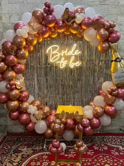 This is one of my most requested bridal shower designs. It features a full circular balloon arch in rose gold and white, a custom "Bride to be" neon sign, and fun accents like a champagne bottle foil balloon, perfect for a chic celebration.