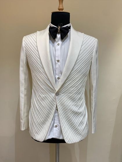 This ivory tuxedo features a unique pleated fabric that creates texture and shadow. It's a sophisticated and unconventional choice for a formal event.