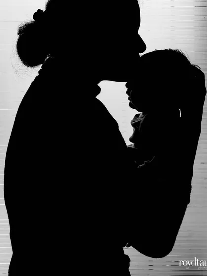 The "after" shot to the pregnancy silhouette. A mother holds her newborn, their shapes silhouetted against the window. This pairing of photos tells a complete and emotional story of the journey to motherhood.