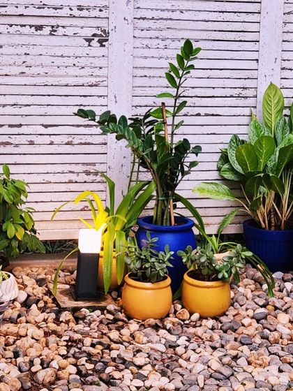 A garden makeover featuring a pebble bed with solar lights and a mix of colorful pots against a rustic white fence.