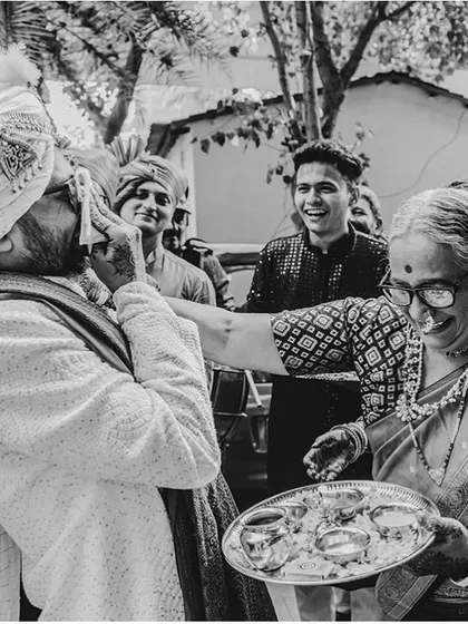 A beautiful, candid moment from a traditional Indian wedding ceremony. A mother-in-law playfully welcomes the groom, capturing the warmth, humor, and love that binds families together.