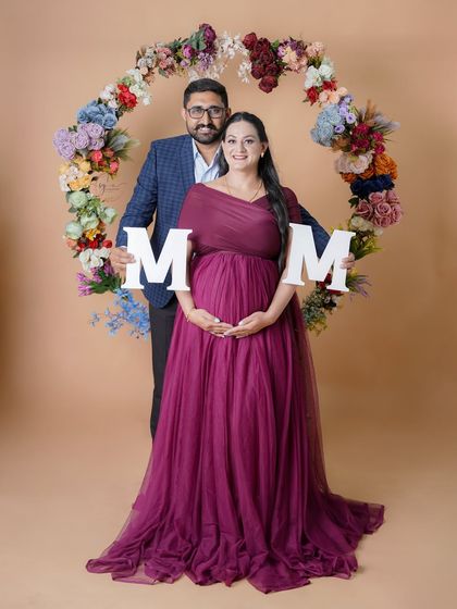 A fun and creative shot where the couple holds up "MOM" letters. Props like these add a playful element to your pregnancy announcement photos.